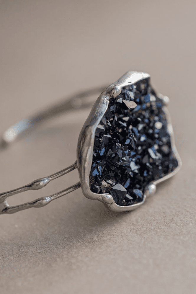 Screenshot of a closeup photo of a silver ring of many small multi-faceted black stones.